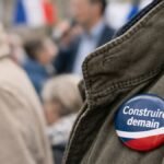 Badge tricolore bleu blanc rouge avec le slogan « Construire demain » porté lors d’un événement politique en France